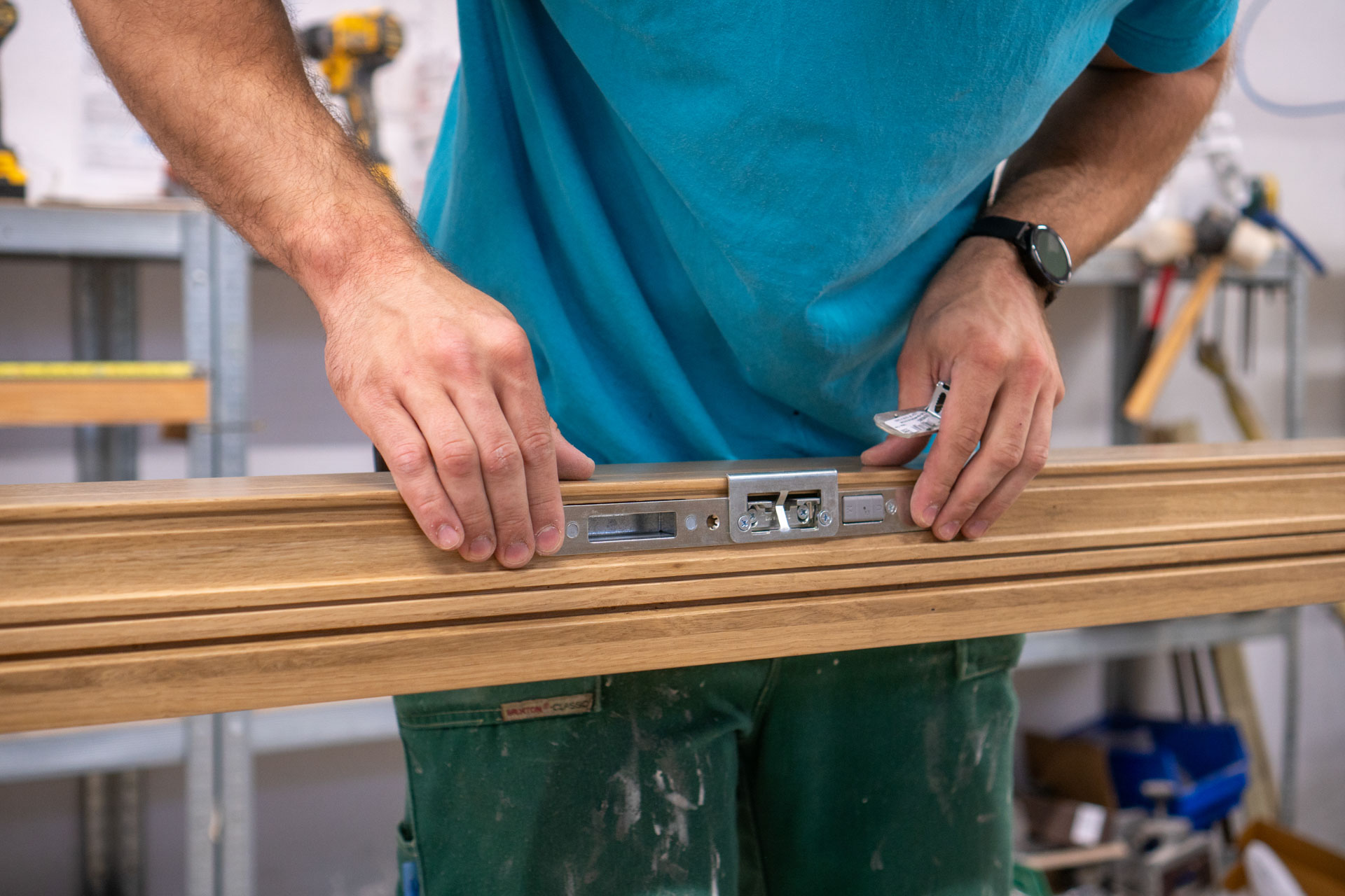 A person in the sashed factory putting a keep on a door jamb