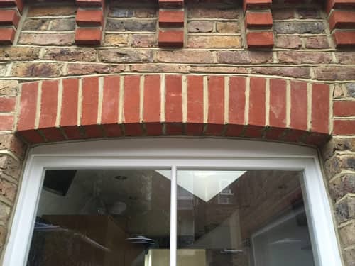 An arch of bricks above a sash window