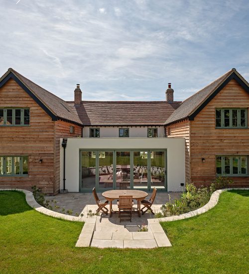 A wooden clad house with bifold doors and timber windows