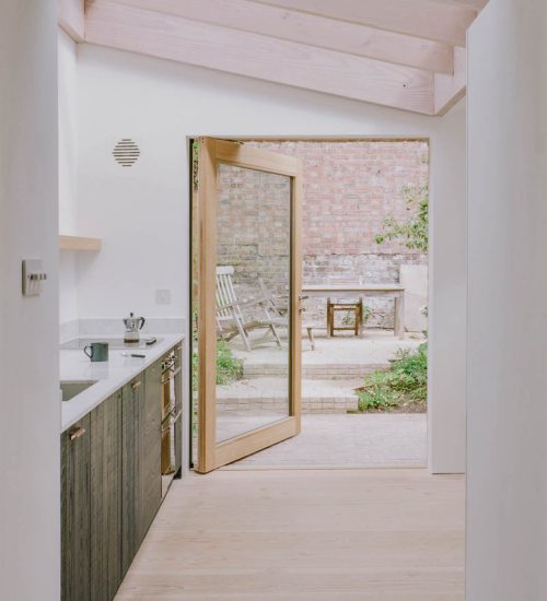 a timber pivot door made by Sashed. in a kitchen opening out