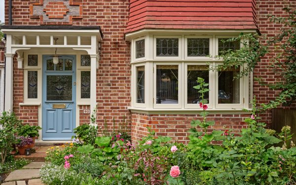 The front of a 1930's house in North West London with a timber casement bay and front door. There is stained glass in both the door and the windows.