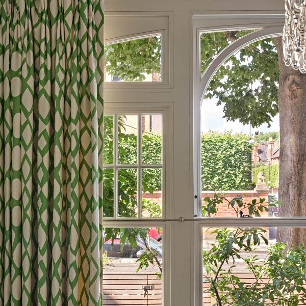 an arched frame timber sash window with curtains either side