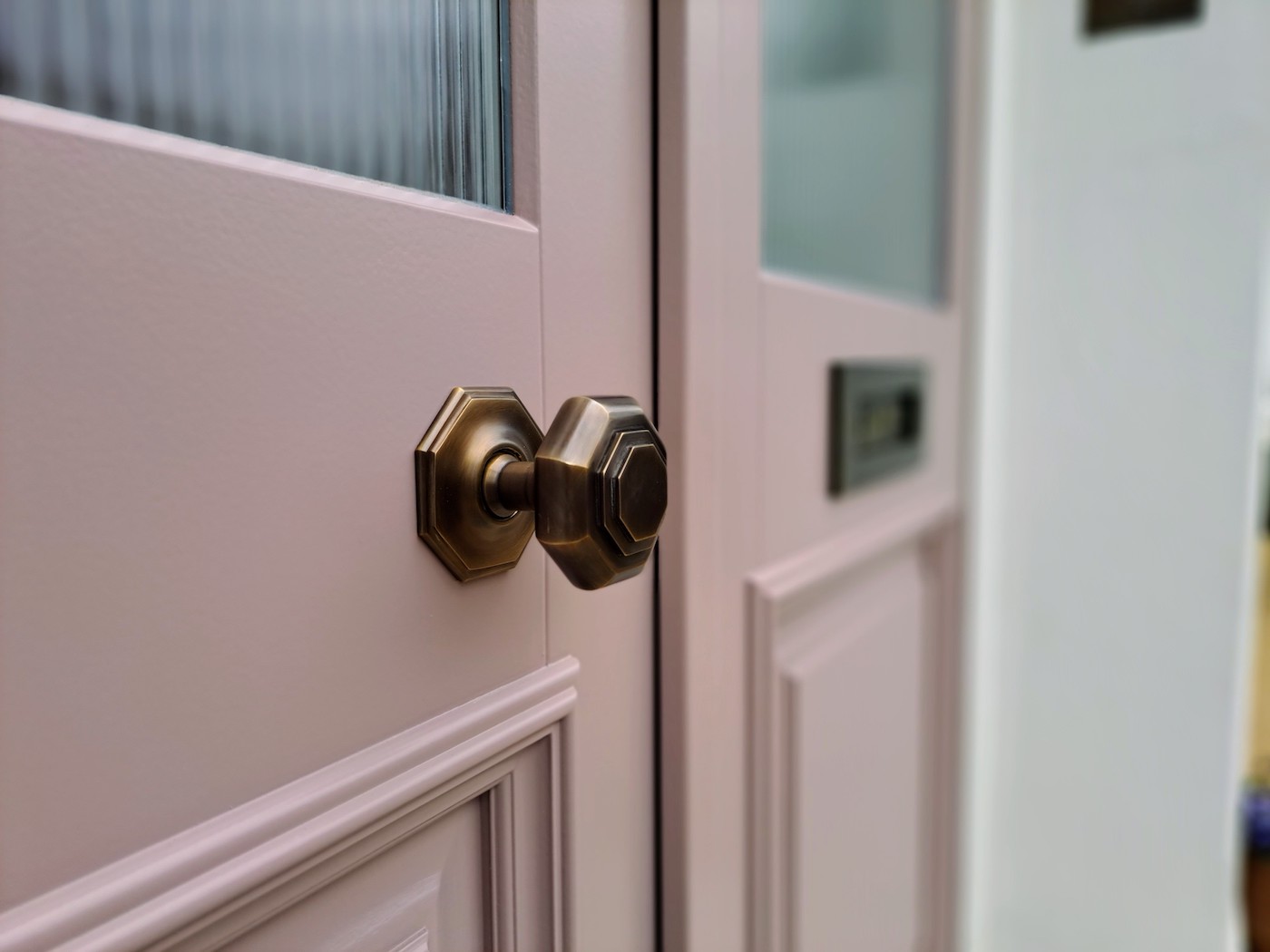 Antique brass door knob on a pink door