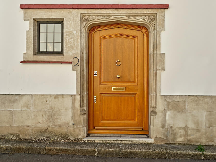 wooden front door with glass fitted at the entrance of a red brick house