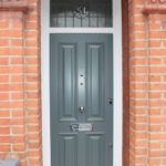 wooden front door grey colour white frame and red brick wall