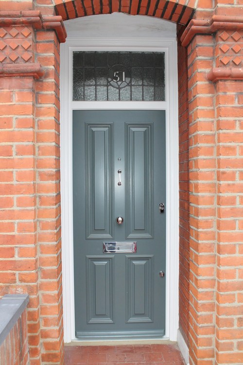 wooden front door grey colour white frame and red brick wall